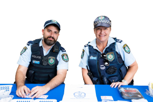 two police officers sitting at a desk and smiling