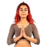 woman with hands pressed together meditating