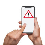 person pointing at a mobile phone with a caution symbol which is a red triangle with a black exclamation in the middle